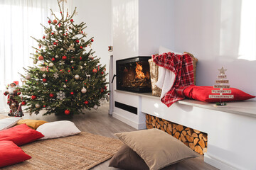 Interior of a modern living room with a burning fireplace, adorned with a Christmas tree and...