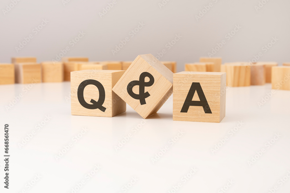 Poster three wooden cubes with q and a symbols on them. white background. in the background there are many 