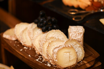 Cheese platter. Deliciour appetizer made of several types of cheese prepared to be served for an event. Appetizer catering food service. Comte, brie, cheddar, camembert cheese along with fruits.