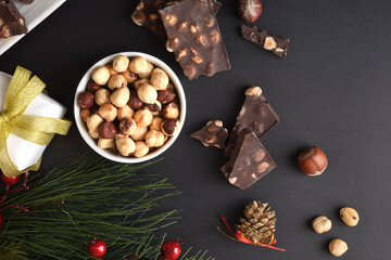 Chocolate with hazelnuts on black christmas table top view