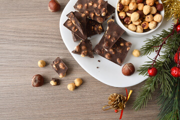 Chocolate with hazelnuts on wooden christmas table top view