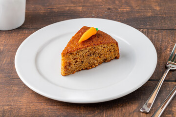 Delicious carrot cake with coffee next to it on wooden table