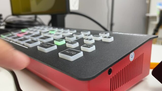 Video switcher equipment mixer console controller on table inside studio. Hand technician pushing buttons