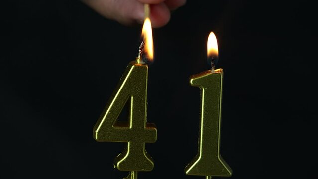 close up on the gold number forty-first candle on a dark background.
