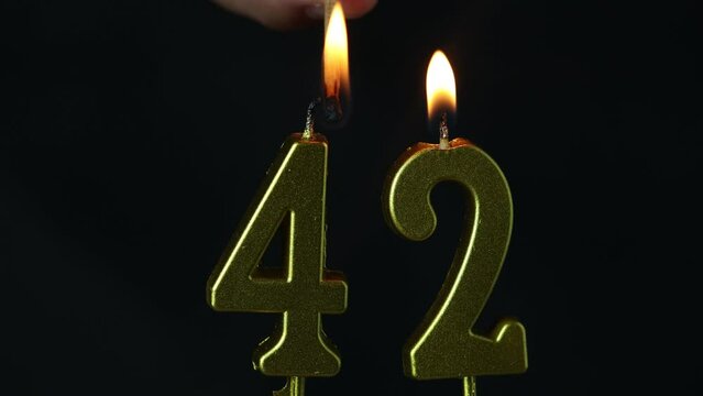 close up on the gold number forty-second candle on a dark background.
