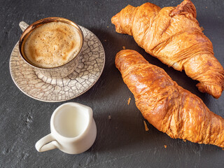 cup of coffee and mini milk mug with pastry aside, simple breakfast concept