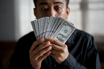 Happy asian man with dollar bills,  a good income, a monetary reward.
