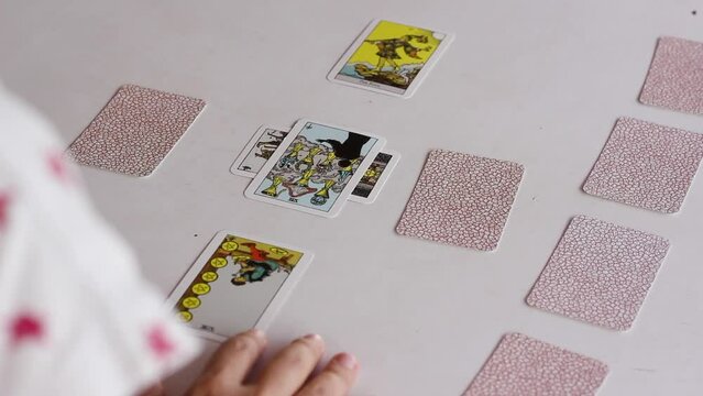 Tarot reader flipping cards of Celtic cross spread, over the shoulder shot