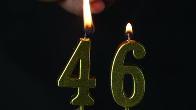 close up on the gold number forty-sixth candle on a dark background.
