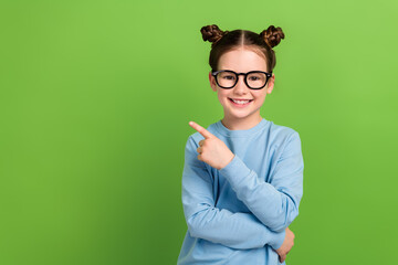 Portrait of cute little girl wearing eyesight specs direct finger empty space september school sale isolated green color background