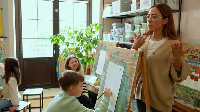 A smiling teacher teaching children an art lesson at an art school