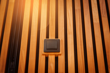 In a close-up view, a light switch is discreetly embedded within wooden acoustic panels