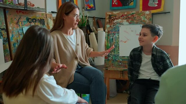 Charming teacher talking with children during an illustration class at art school