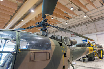 Military helicopter stand inside big pavilion