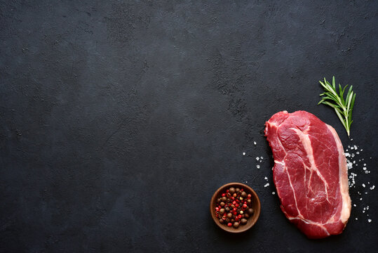 Raw organic marbled beef steak with spices. Top view with copy space.