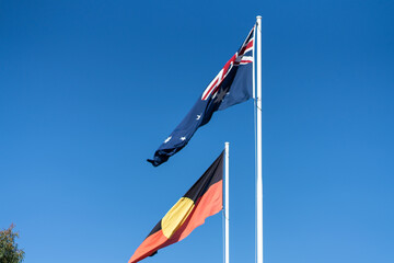 The Commonwealth of Australia Flag and the First Australians Aboriginal Flag Flying Together in the Wind - obrazy, fototapety, plakaty
