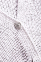 Handmade white patent brioche stitch knitting cotton texture background. Part of cardigan with buttons. Top view of knitting clothes