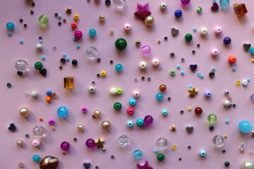 Various colorful beads on bright pink background. Top view.