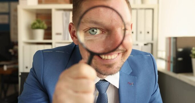Young smiling businessman looks through magnifying glass. Creative ideas for business concept
