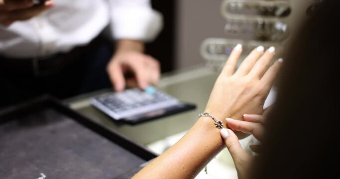 Jewelry store and woman trying on silver bracelet closeup. Choosing jewelry in salon