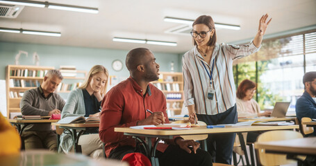 Young Teacher Checking Up on a Black Male, Helping Him with a Task, Complimenting His Work. Modern...