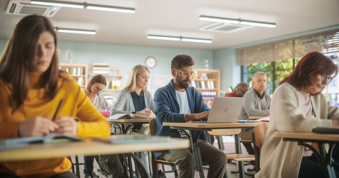 Attentive Indian Student Listening to Tutor and Writing Down Lecture on Laptop Computer in Class. Grown Up Men and Women Getting Specialty Knowledge on a Part-Time Course in Modern College.