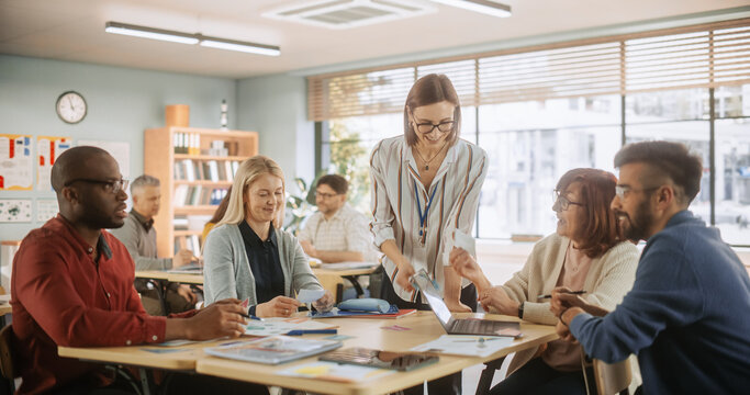 Grown-Up Men and Women Working in Groups for an Assignment in Specialty Development Center. Adult Classmates Working on a Team Assignment, Young Female Teacher Explaining the Exercise Objectibves