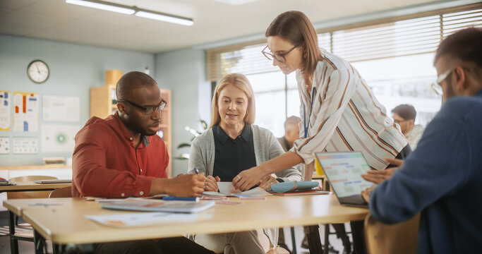 Grown-Up Men and Women Working in Groups for an Assignment in Specialty Development Center. Adult Classmates Working on a Team Assignment, Young Female Teacher Explaining the Exercise Goals.