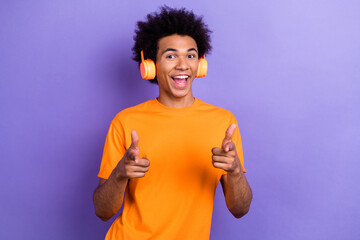 Photo of funky young man listen sony wireless earphones indicate fingers you cool hi welcome come...