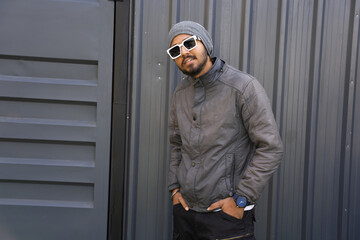 handsome looking young indian men wearing warm winter clothes posing with glasses. Standing isolated over black background
