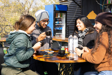 Group of happy indian friends wearing winter cloths having a coffee together in cappuccino...