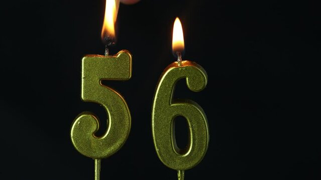 close up on the gold number fifty-sixth candle on a dark background.
