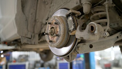 A modern car in a car service on a lift with a wheel removed. Elements of the brake system and suspension. Brake pad repair, car on a lift, close-up.