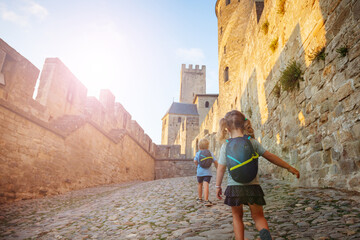 Kids hurry to explore Carcassonne castle walls at summer sunset