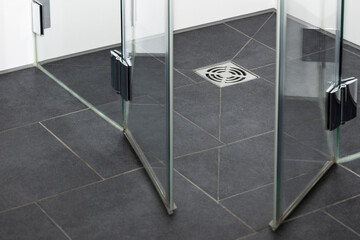 Drain Floor  in Modern Shower.Modern Shower Cabin with Glass Shower  Door on Gray Tiled Floor and...