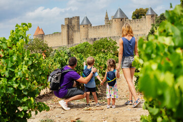Happy children admire Carcassonne stone walls and old towers - obrazy, fototapety, plakaty