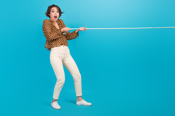 Photo of surprised lady playing tug war pull heavy string isolated on blue color background