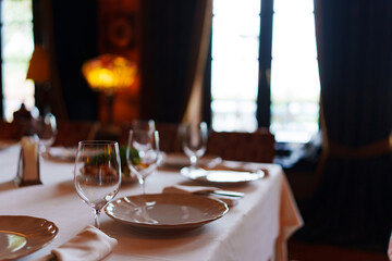 An empty wine glass and plates on a table served for a banquet. 