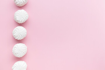 Soft white vanilla zephyr on light pink table. Pastel color. Banner with empty space for the text