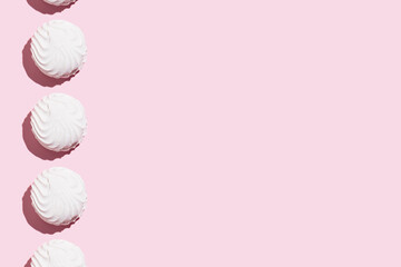 Soft white vanilla zephyr on light pink table. Pastel color. Banner with empty space for the text