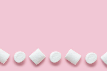 Row of white marshmallows pattern on light pink table background in hard light. Pastel color