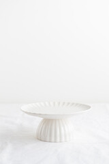 Empty tableware - white plate cakestand on white table as a background for a dessert