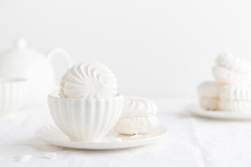 White airy zephyr or marshmallow shells on a plate on a white table, banner with space for text