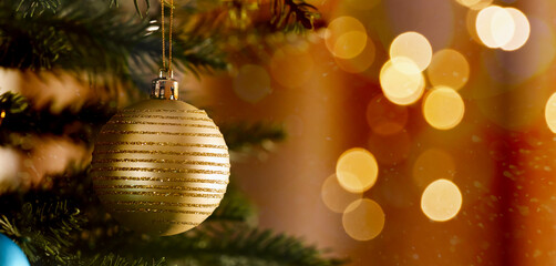 Obraz na płótnie Canvas Shiny bauble on Christmas tree branch against blurred lights, bokeh effect. Banner design with space for text