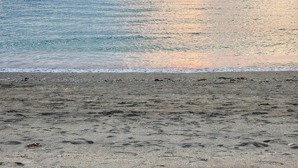 Very early morning at the calm sea shore beach with tiny waves and clear water and sky