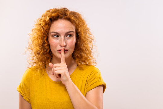 Portrait of a beautiful ginger woman with finger on her lips