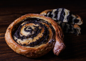 Two poppy seed buns whole and cut on a wooden background.