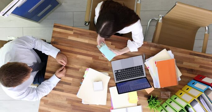 Woman sitting at workplace and refusing money in envelope in office top view. Offered by man and wants to bribe employee