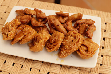 Moroccan chebakias on a white plate in a patio with plants