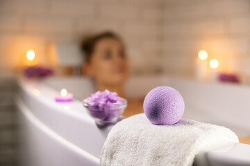 home spa. woman relaxing in bathtub in candle light and using bath bomb and sea salt crystals for...